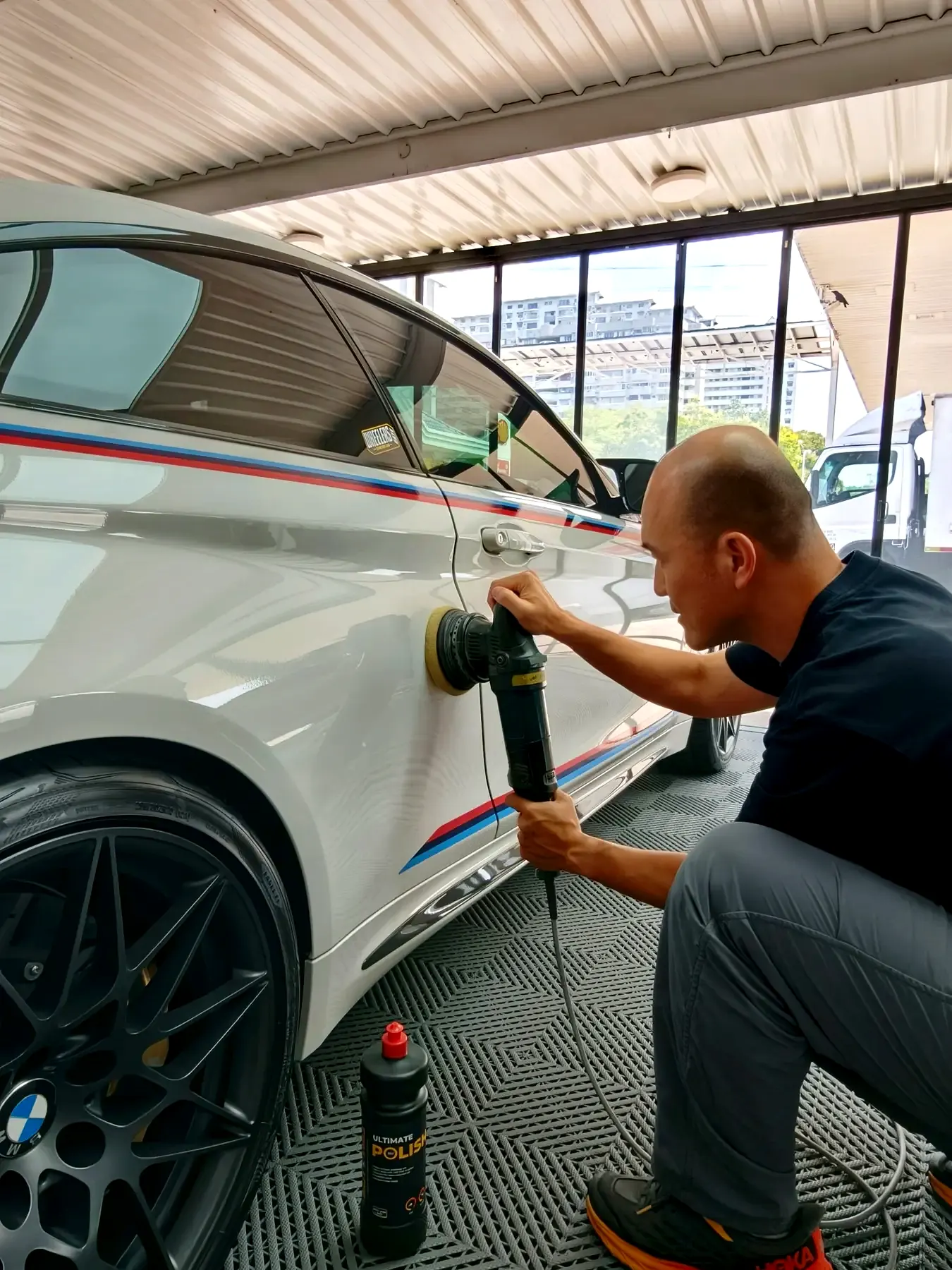 Detailer polishing the side of a white BMW at WG Detailing