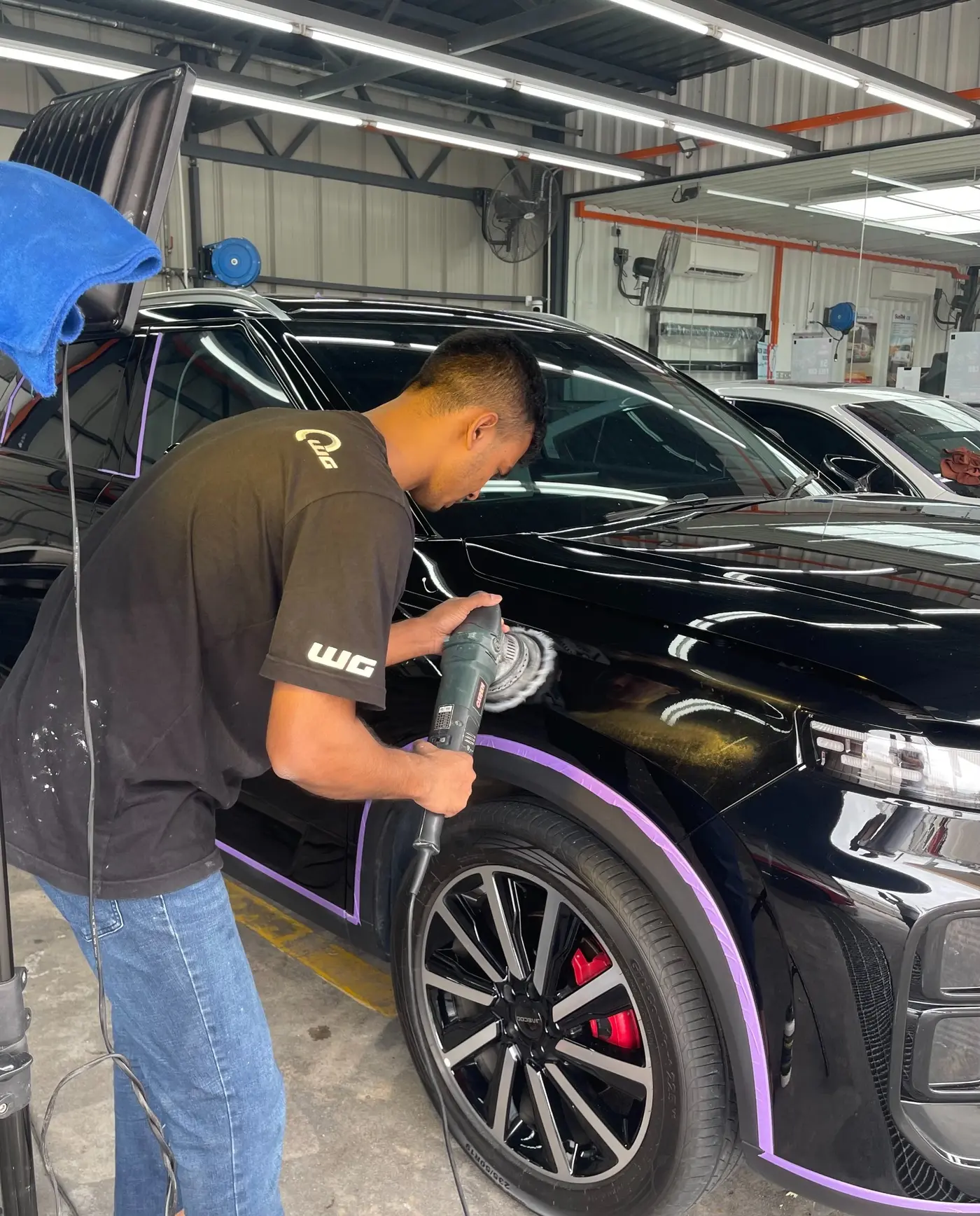 WG Detailing technician machine polishing a black vehicle