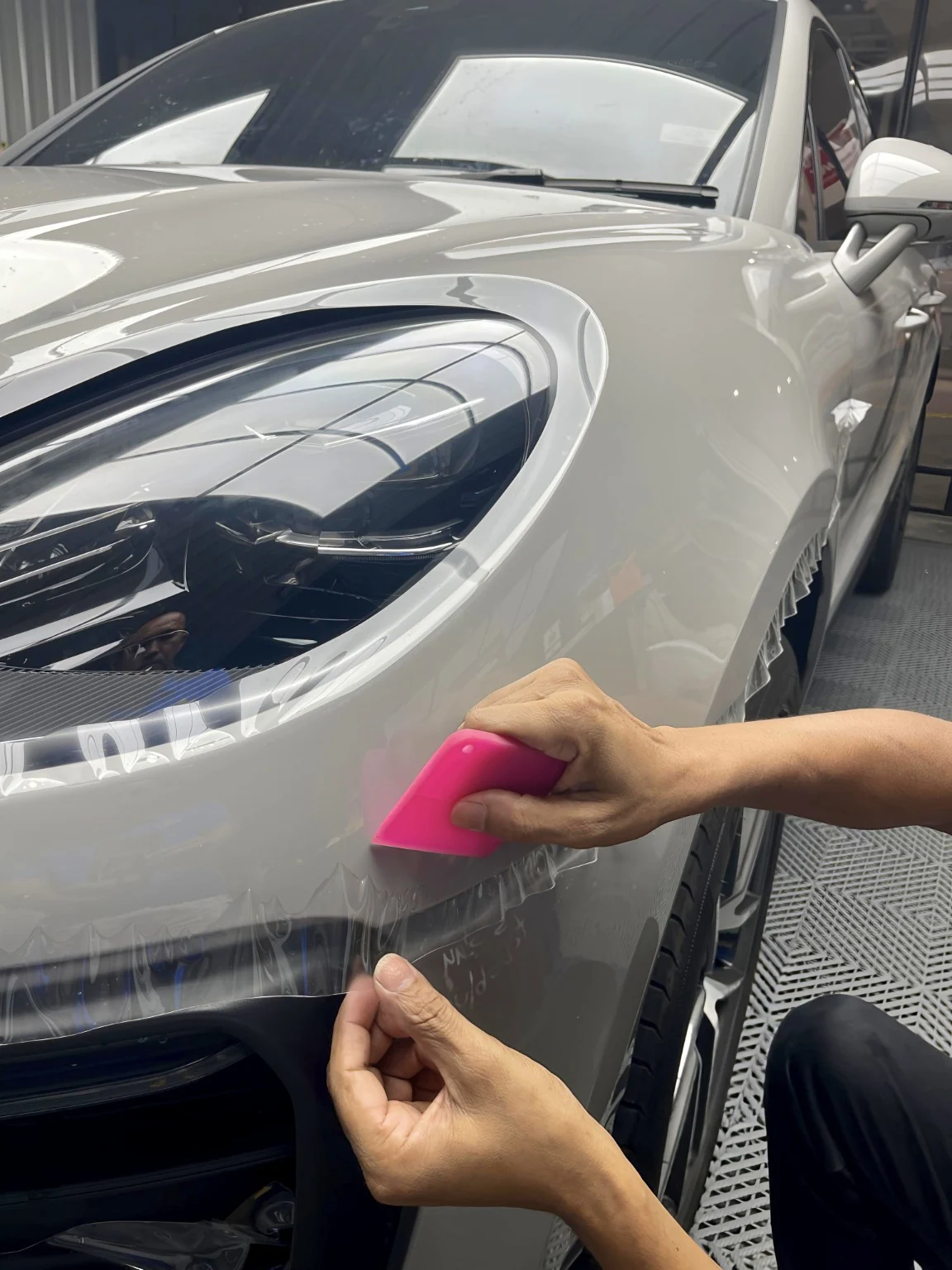 Technician applying paint protection film to a vehicle panel at WG Detailing
